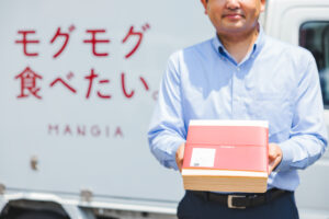 冷蔵車を背景にしてドライバーがお弁当をお届けしている様子